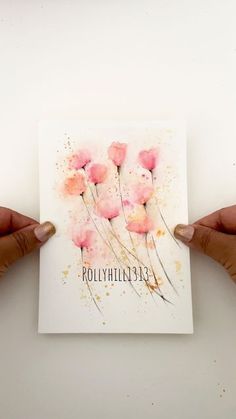 two hands holding up a card with watercolor flowers