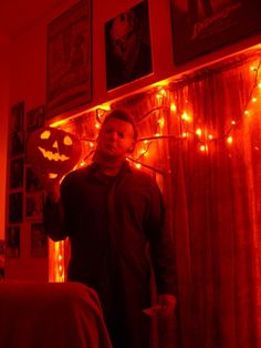 a man standing next to a bed in a room with halloween decorations on the wall