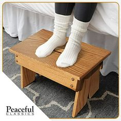 a person sitting on top of a wooden step stool with their feet up and legs down