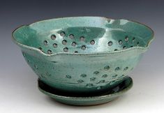 a green ceramic bowl with holes in it