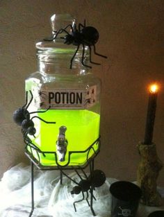 a jar filled with yellow liquid sitting on top of a table next to a candle