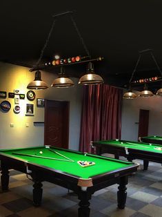 several pool tables with lights hanging from the ceiling