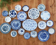 a collection of blue and white plates sitting on top of a wooden floor