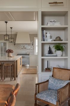 an open kitchen and living room with white walls, wood furniture and shelves filled with books