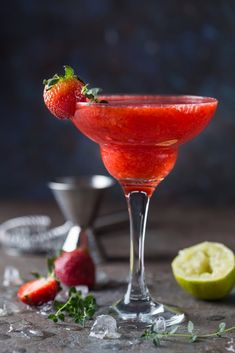 a close up of a drink in a wine glass with strawberries on the rim