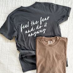 Feel the Fear and Do it Anyway. ✨ I'm a big believer in doing things before you're ready. Nothing great ever happens when you're in your comfort zone. You never know unless you try! Whether it's life, motherhood, business ... you just have to go for it. 100% cotton Comfort Colors tee that gets softer with every wash. Tone on tone embroidery on front; printed on back. Available for a limited time. - Comfort Colors Tee - Medium Weight - Gets softer with every wash - Size up for a stylish oversized Inspirational Cotton Tops With Text Print, Sporty Cotton T-shirt With Funny Text, Inspirational Short Sleeve Tops With Funny Text, Inspirational Cotton Tops With Slogan, Inspirational Black Cotton Tops, Inspirational Cotton Tops With Screen Print, Inspirational Cotton Slogan Tops, Inspirational Cotton Top With Screen Print, Inspirational Crew Neck Cotton Shirt