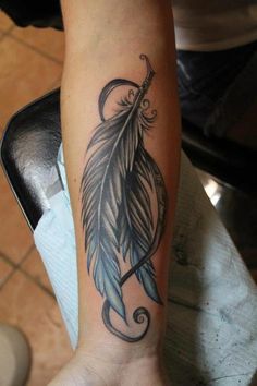 a woman's foot with a tattoo on it and a feather in the middle