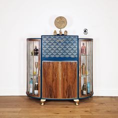 a blue cabinet with bottles in it on top of a wooden floor next to a white wall