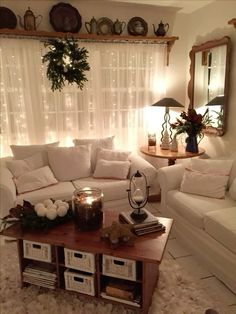 a living room with white furniture and christmas decorations on the table in front of a window