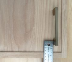 a wooden cabinet door with a measuring tape on the bottom and an angle ruler in front of it