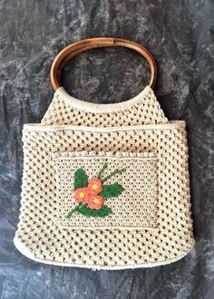 Adorable vintage macrame bag that is simple and sweet.  Details include: The body is ivory with a floral applique in a peachy pink, yellow and green The floral applique is on a patch pocket on one side of the bag that measures 7 inches wide by 5 1/4 inches tall Fully lined in ivory colored guaze fabric One small 4 1/4 inch by 5 1/4 inch pocket sewn into the lining Oval top handle made of bamboo Makers label is MCL Made in the Phillippines I believe that it was made in the 1970's The condition is Vintage White Crochet Bag For Summer, Vintage Crochet Shoulder Bag For Summer, Vintage Beige Rectangular Crochet Bag, Vintage Beige Crochet Tote Bag, Vintage Beige Crochet Bag For Summer, Vintage Natural Crochet Bag, Beige Vintage Crochet Bags, Beige Crochet Macrame Bag For Spring, Vintage Crochet Beach Bag