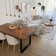 a living room filled with furniture and a wooden table surrounded by white chairs next to a couch