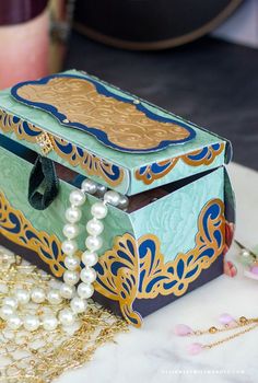 a jewelry box sitting on top of a table next to pearls and other items in front of it