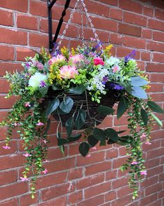 a basket filled with flowers hanging from a brick wall