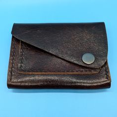 This stylish handmade brown leather wallet is the perfect accessory for anyone. The wallet features a sleek design with a sturdy antique nickel snap closure, keeping your belongings secure while adding a touch of sophistication to your look.  With a single card slot on the front and a spacious main compartment, this wallet is both practical and fashionable, making it ideal for everyday use. Upgrade your accessory game with this timeless piece that will never go out of style. Length:  4.75" Width Brown Trifold Wallet For Everyday Carry, Vintage Brown Wallets With Card Slots For Daily Use, Vintage Brown Wallet With Card Slots For Daily Use, Vintage Brown Wallets For Daily Use, Distressed Brown Rectangular Wallet For Everyday Use, Brown Waxed Finish Wallets For Everyday Carry, Distressed Brown Rectangular Wallet, Everyday Rectangular Distressed Brown Wallet, Handmade Brown Wallet For Everyday Carry