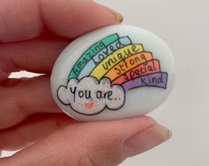 a hand holding a button with the words you are special kind in rainbows on it