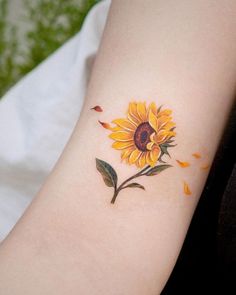 a yellow sunflower tattoo on the left arm and right arm with leaves around it