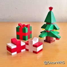 three small christmas trees made out of legos sitting on a wooden table next to each other