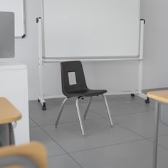 a black chair sitting in front of a whiteboard on the floor next to two desks