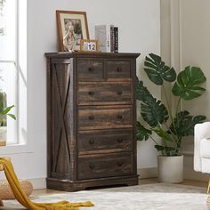 a wooden chest of drawers sitting next to a chair and potted plant in a living room