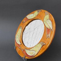 a wooden mirror with birds painted on it