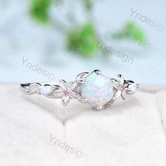 a white opal ring with leaves and flowers on the side, sitting on top of a