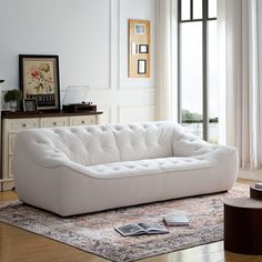 a white couch sitting on top of a rug in a living room next to a window