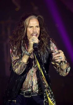 an image of the singer with long hair holding a microphone in his hand on stage