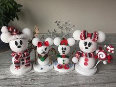 three snowmen with hats and scarfs on sitting next to each other in front of a potted plant