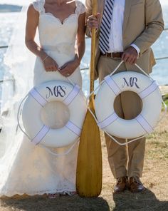 a man and woman standing next to each other in front of the ocean with life preservers