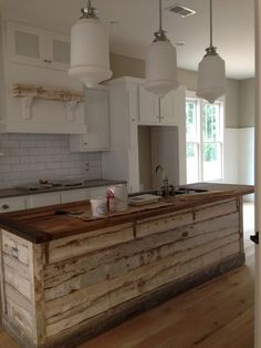 a kitchen island made out of wooden planks with lights hanging from the ceiling above it