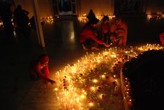 several people sitting around a table with candles on it and one person kneeling down in front of them