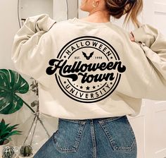 a woman wearing a white sweatshirt with the words halloween town printed on it, in front of a mirror