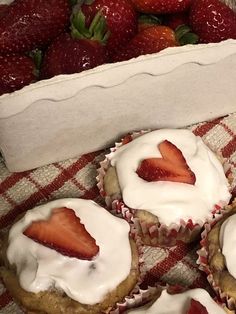 strawberries and cupcakes are sitting on a checkered tablecloth