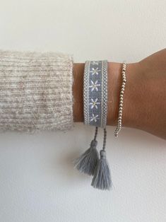 a woman's arm with three bracelets and two tassels on it