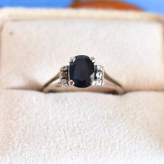 an engagement ring with a blue stone surrounded by three white diamonds in a gift box