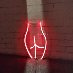 a red neon sign sitting on top of a wooden table next to a brick wall