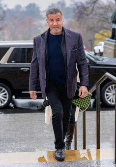 an older man walking down the street with his hand in his pocket and wearing a purple blazer