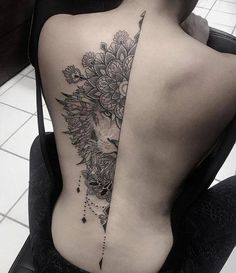 a woman's back with a lion and flowers tattoo on her left side ribcage