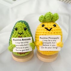 two crocheted pineapples with words on them sitting next to each other