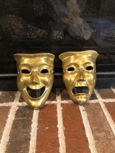 two golden masks sitting on top of a tiled floor