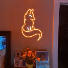 a neon sign that is on the wall next to a vase with flowers in it