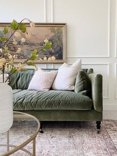 a living room with a green couch and painting on the wall