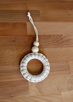 a white rope and wooden bead hanging on a wood floor