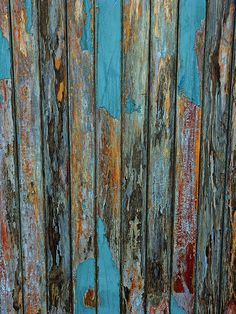 an old wooden fence with peeling paint and rust on the top part of it's boards