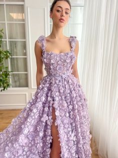 a woman wearing a purple dress with flowers on the skirt and thigh high slits