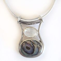 Paua Shell and Rainbow Moonstone have always been the perfect pairing! Colorful swirls throughout the shell match the flashes in the Rainbow Moonstone! This pendant is just over 1" long and will come with a sterling Silver Chain! It was designed by Marianna and Richard and handmade by the Artisans of Bali!  The pendant is being sold by the designers themselves! Silver Mother Of Pearl Necklace With Gemstone, Silver Jewelry With Natural Stones And Mother Of Pearl, Silver Necklace With Large Round Stone, Colorful Swirls, Paua Shell, Shell Pendant, Fine Jewellery Necklace, Sterling Silver Chain, The Rainbow