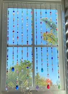 a window with beads hanging from it's side and palm trees in the background