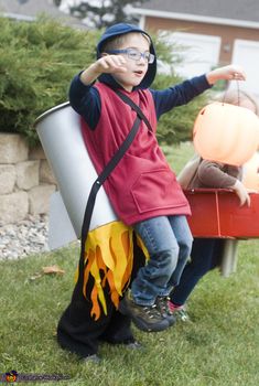 a young boy dressed up as a fireman and holding a pumpkin in his hand