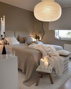 a large bed sitting in a bedroom next to two candles on top of a table